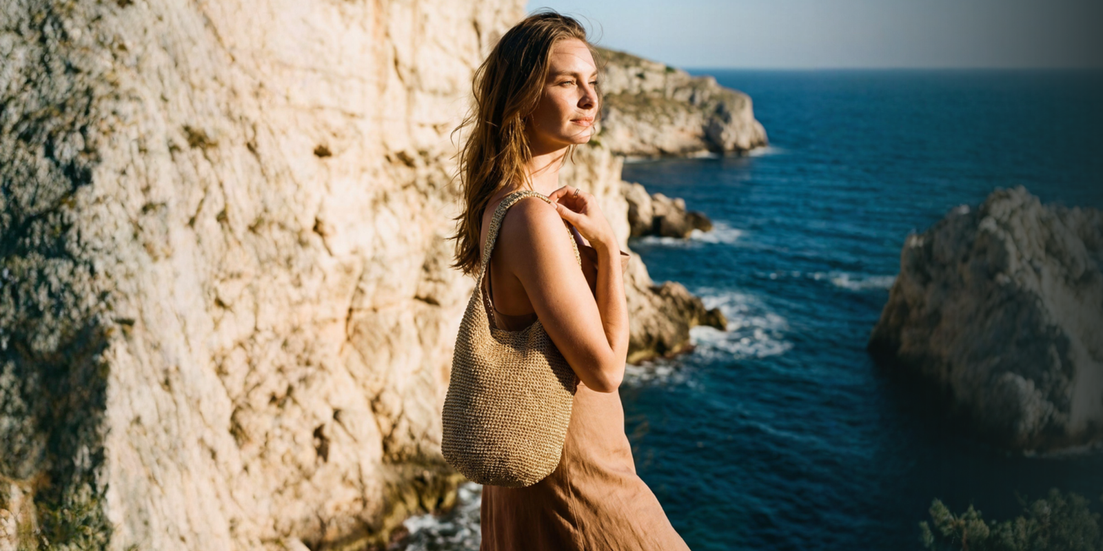 Woman standing on a rocky cliff overlooking the ocean
