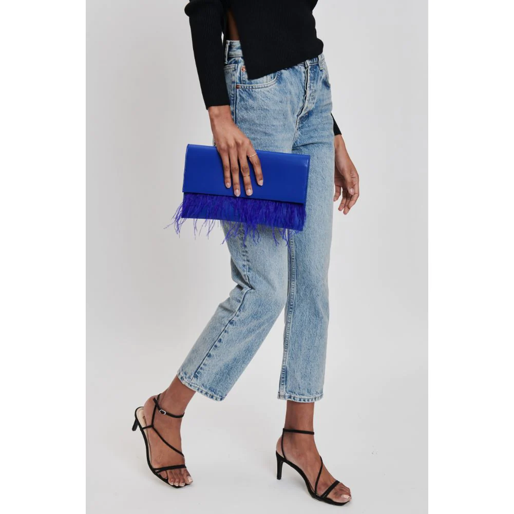 a woman in jeans and heels holding a blue furry bag