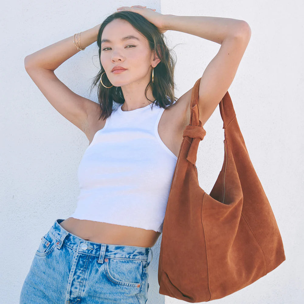 a woman putting her hands on her head with a fashion handbag around her arm